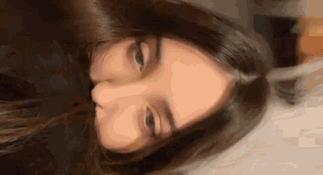 a close up of a woman 's face with her eyes closed and her hair blowing in the wind .