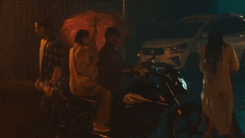 a group of people standing around a motorcycle and a car