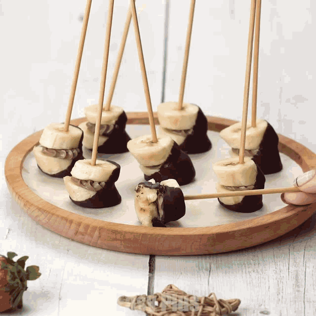 a person is dipping a banana in chocolate on a wooden tray