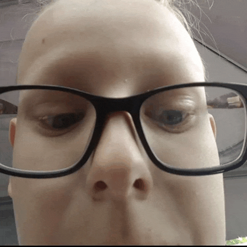 a close up of a person wearing glasses with a reflection of a car