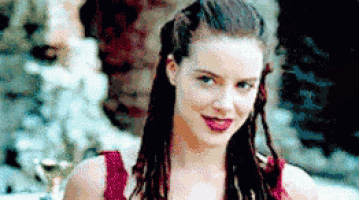 a woman in a red tank top is smiling and looking at the camera .