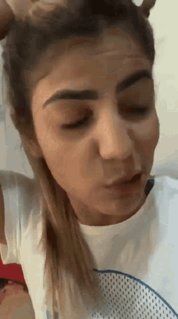 a close up of a woman 's face with her eyes closed and a white shirt on