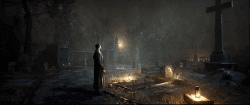 a man stands in a cemetery at night with a cross in the background