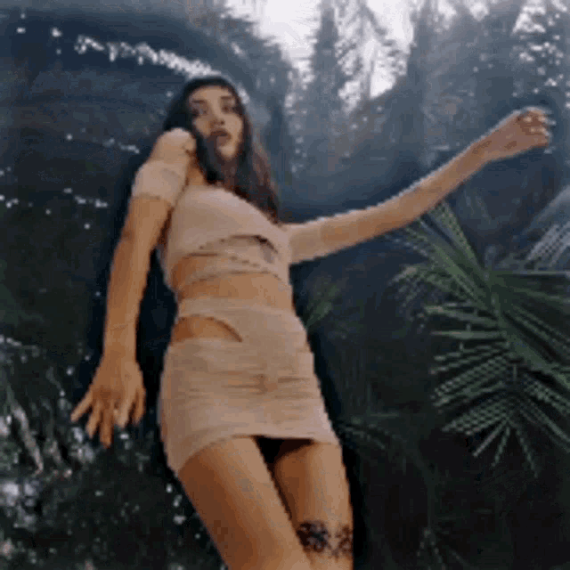a woman in a crop top and short skirt is dancing in the woods