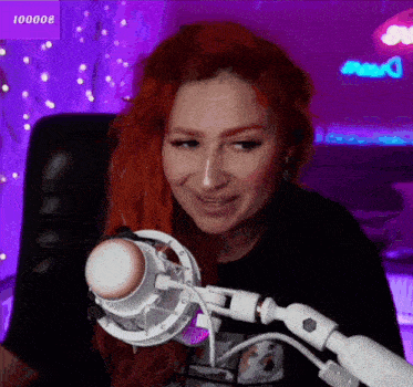 a woman with red hair is sitting in front of a microphone with a purple background behind her that says 100008