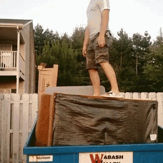 a man stands on top of a dumpster that says wabash on it