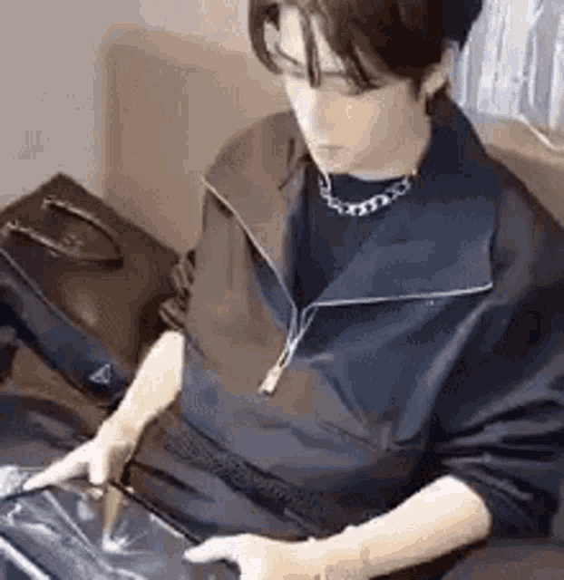 a man is sitting on a couch looking at a tablet .
