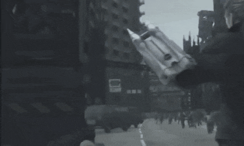 a black and white photo of a man holding a gun in a city street .