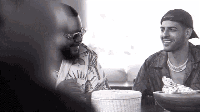 a black and white photo of two men sitting at a table laughing
