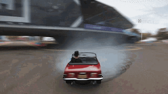 a red car is driving under a bridge with a sign that says festival site on it