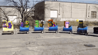 a toy train is going down a road with a building in the background