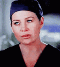 a close up of a woman wearing a scrub top and a hat .