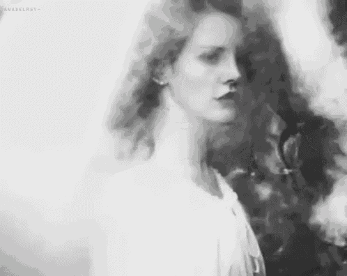 a black and white photo of a woman with long hair in a white dress .