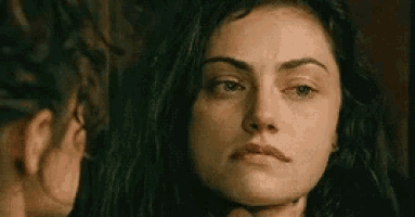 a woman is looking at herself in a mirror and holding her neck .