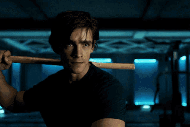 a man in a black shirt is holding a wooden stick over his head