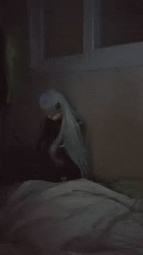 a doll with long white hair is sitting on a bed in a dark room
