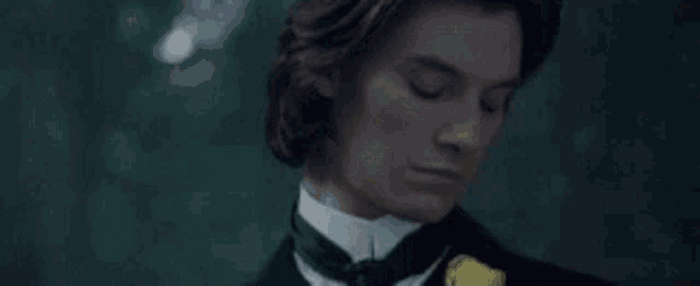 a young man in a tuxedo with a yellow flower on his lapel is looking down .