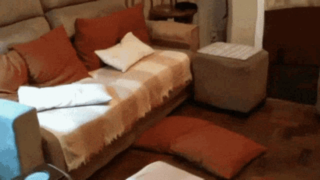 a living room with a couch and ottomans and pillows on the floor