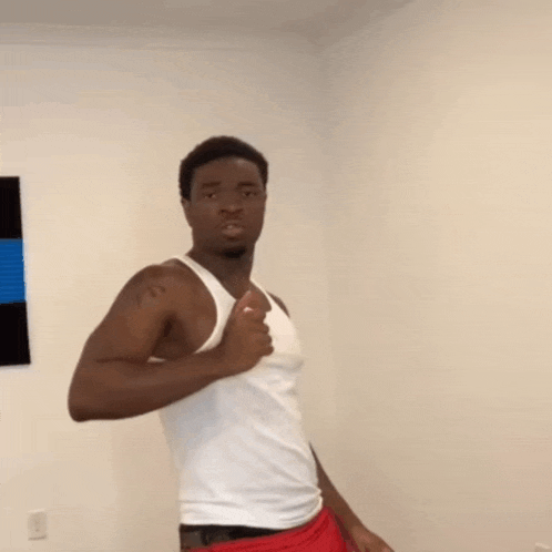 a man in a white tank top and red shorts is standing in a room