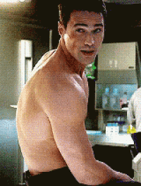 a shirtless man is sitting in a kitchen