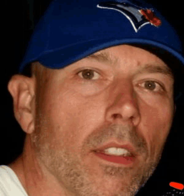 a close up of a man wearing a blue jays baseball cap
