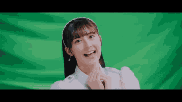 a girl with a headband on her head is smiling in front of a green screen