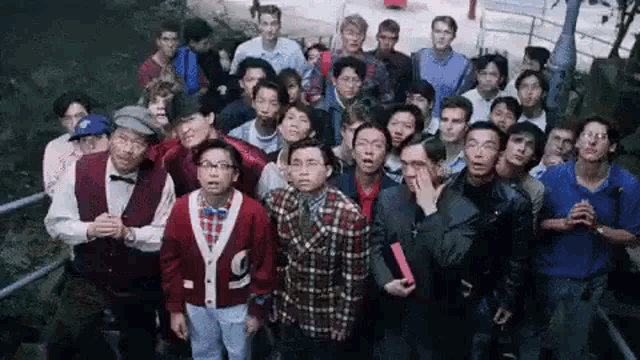 a large group of people are standing next to each other in a park .