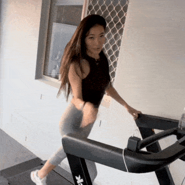 a woman is walking on a treadmill that has the letter k on it
