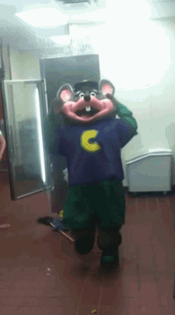 a chuck e cheese mascot in a purple shirt with the letter c on it