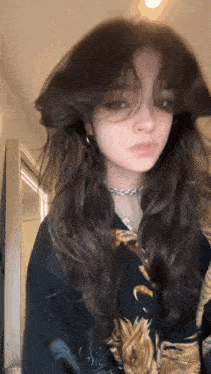 a girl with long dark hair is wearing a necklace and earrings .