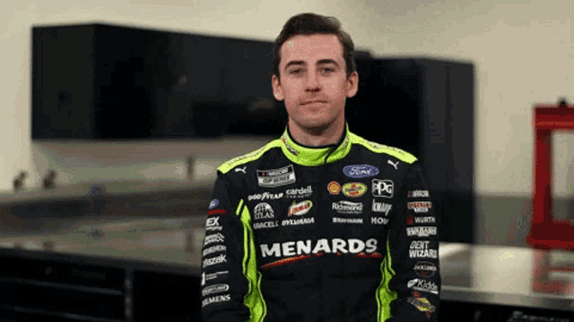 a man wearing a menards jacket stands in a room