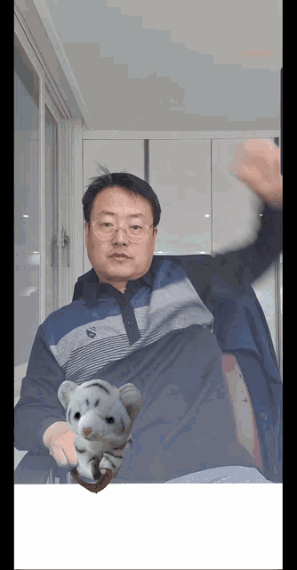 a man in a blue shirt holds a stuffed tiger in his hands