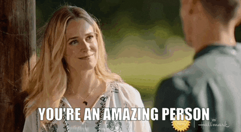 a woman is standing next to a man and smiling and says you 're an amazing person .