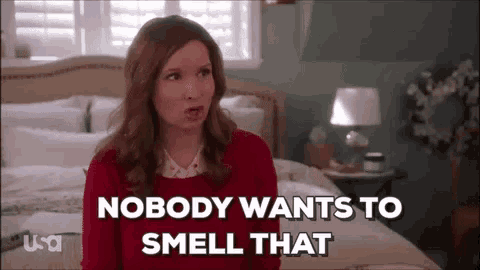 a woman in a red sweater is sitting on a bed in a bedroom .