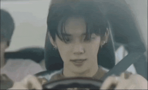 a young man is driving a car and smiling .