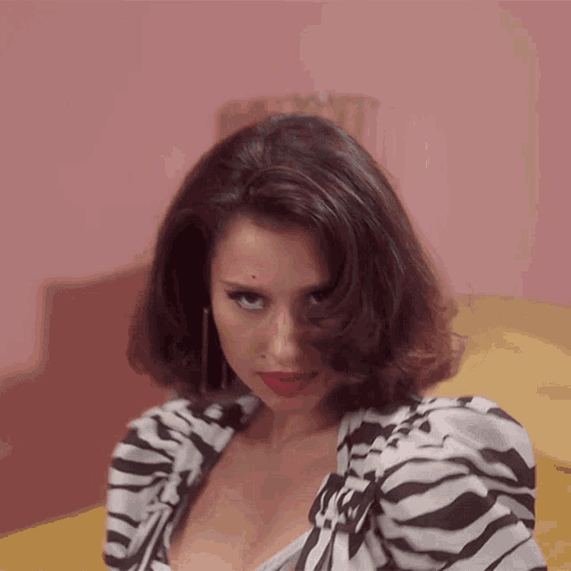 a woman wearing a zebra print top and red lipstick looks at the camera
