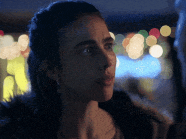 a close up of a woman 's face with blurry lights behind her