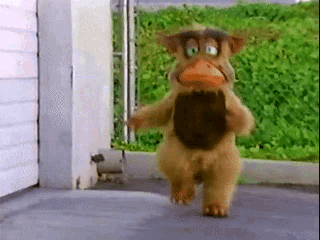 a cartoon character is running down a sidewalk in front of a garage door .