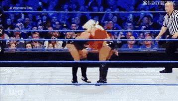 two wrestlers are fighting in a wrestling ring while a referee watches