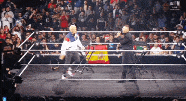 two men in a wrestling ring with a sign that says w live