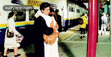 a couple hugging in front of a train that says west express
