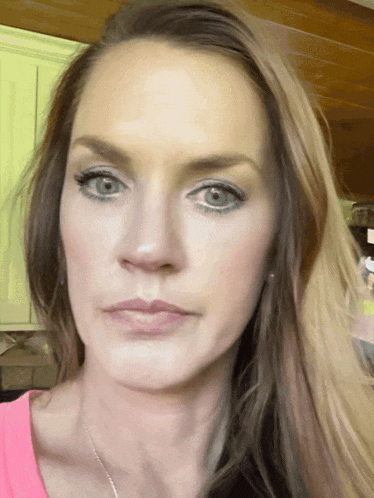 a close up of a woman 's face with a pink shirt