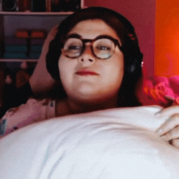 a woman wearing headphones and glasses is laying on a bed