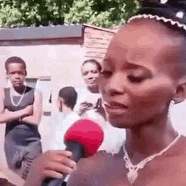 a woman is holding a microphone in front of a crowd of people .