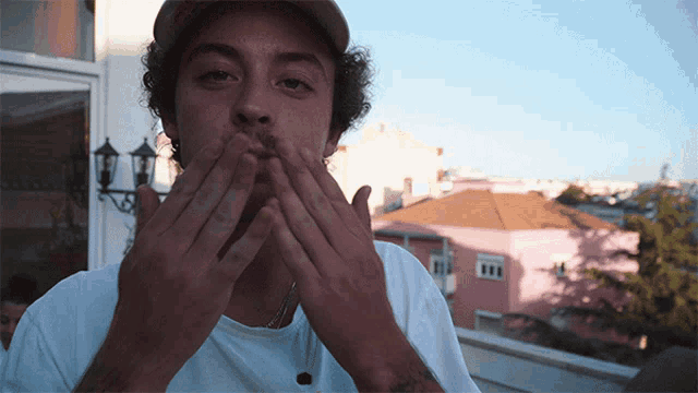 a man covering his mouth with his hands while wearing a white shirt