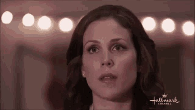 a close up of a woman 's face with a blurred background of lights .