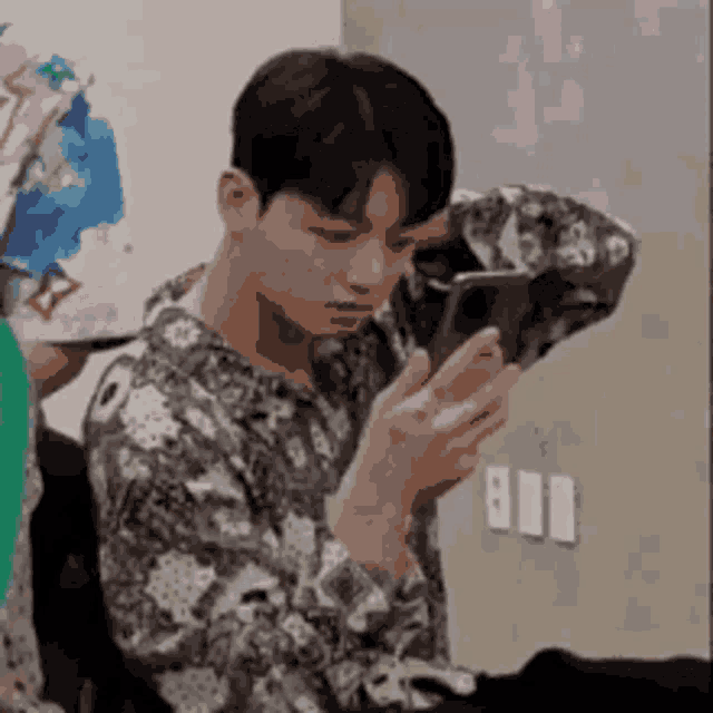 a young man is looking at his cell phone while sitting in a chair .