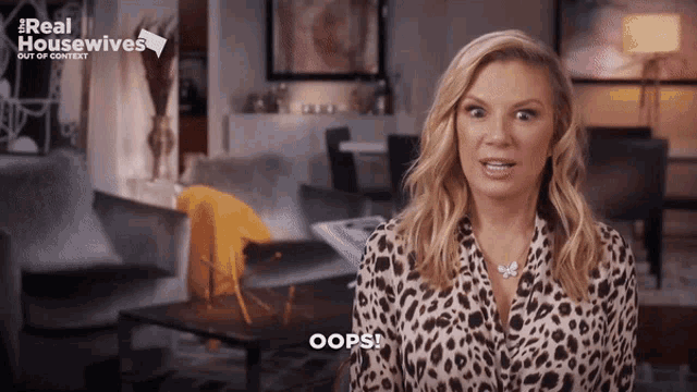 a woman in a leopard print shirt says oops in front of a sign that says real housewives