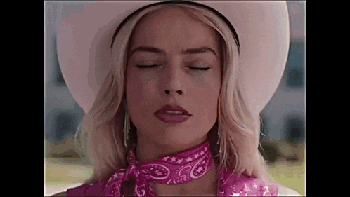 a woman wearing a cowboy hat and a pink bandana is making a funny face with her eyes closed .
