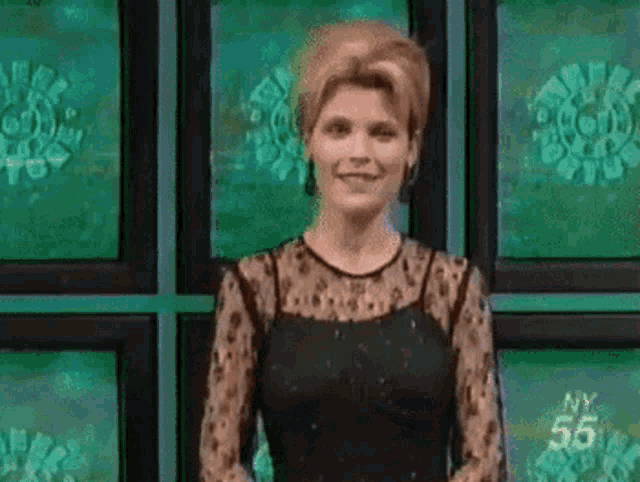 a woman in a black dress is standing in front of a wall of green screens with the number 55 on them